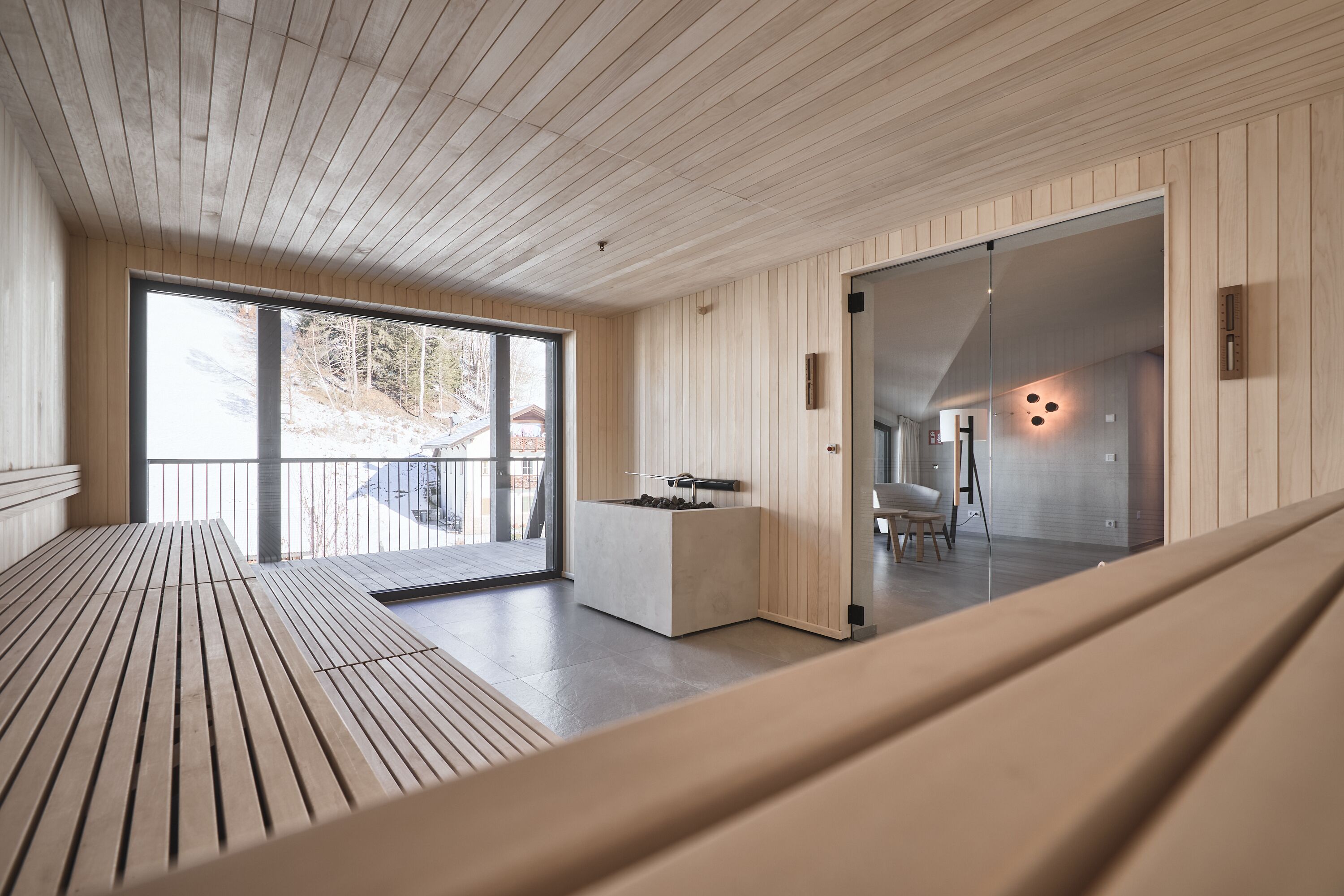 Ein modernes Interieur mit Holzbalkendecke, großen Fenstern und einer Sitzecke.