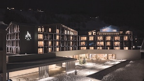 Un hotel moderno con fachada de vidrio, varios niveles y un patio cubierto de nieve.