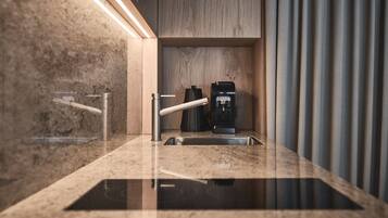 Una cocina moderna con encimera de mármol, grifo de acero inoxidable y cafetera.
