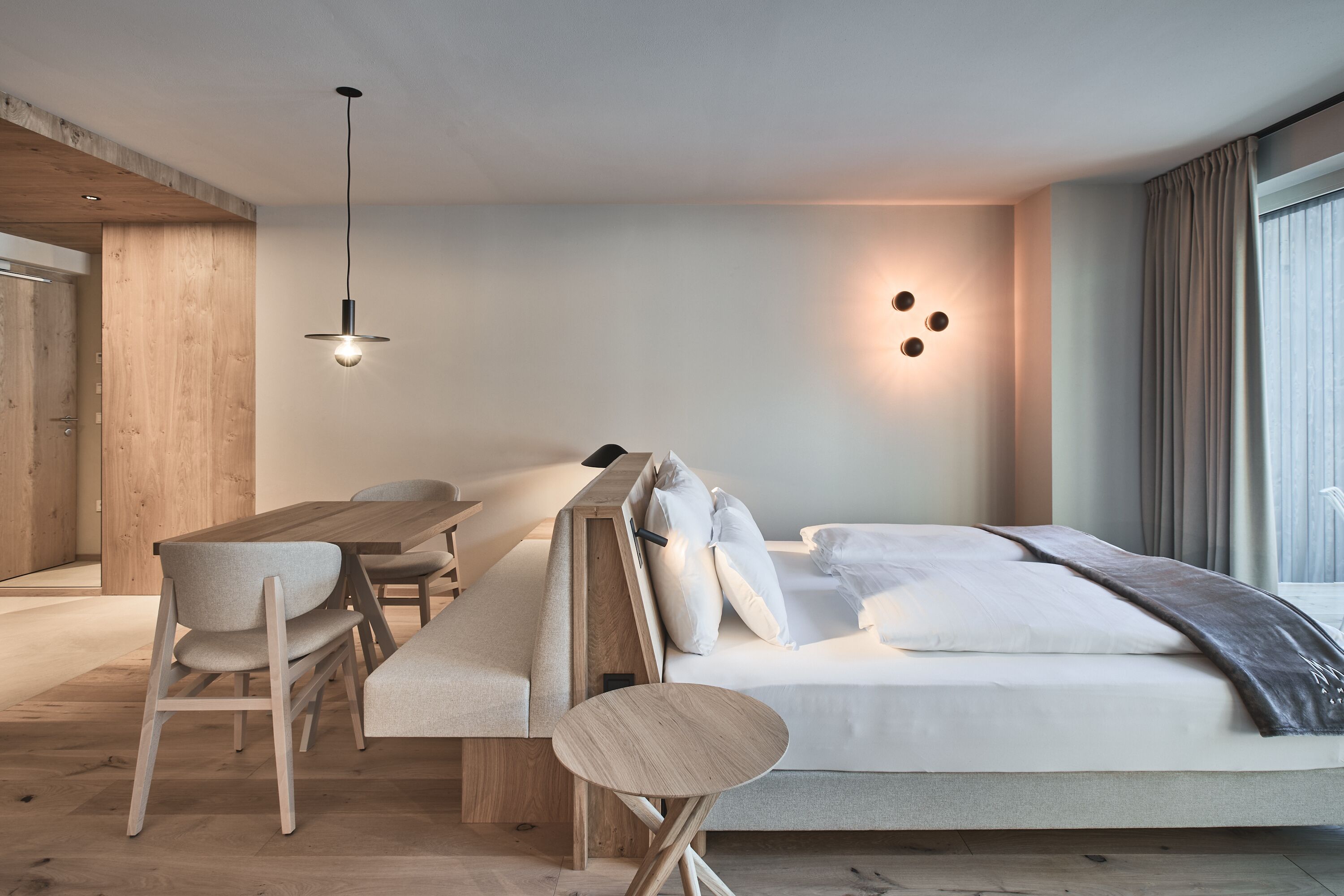 A modern bedroom with a wooden bed, a desk, and chairs.