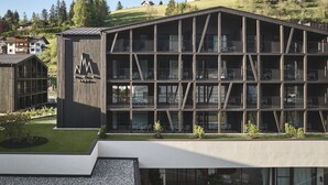 Un edificio moderno de varios pisos con balcones, un área verde y una vista despejada del paisaje circundante.