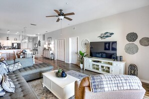 A modern living room with a sectional sofa, a coffee table, and a television. - New! Elegant Waterfront Charmer ~ 402 Island Key (Clearwater)