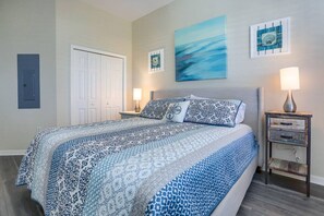 A bedroom with a bed, two bedside tables, a door, and wall art.