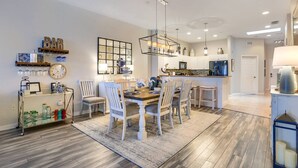 Uma cozinha moderna com uma ilha central, armários brancos e um lustre.