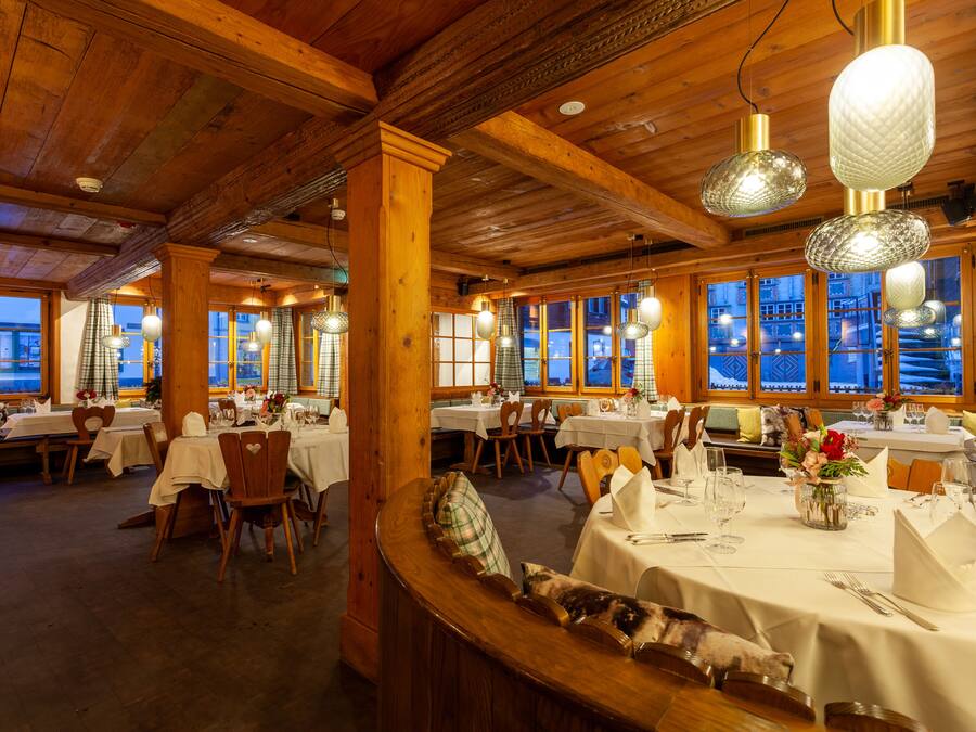 Ein Restaurant mit Holzvertäfelungen, mehreren gedeckten Tischen und großen Fenstern mit Ausblick.