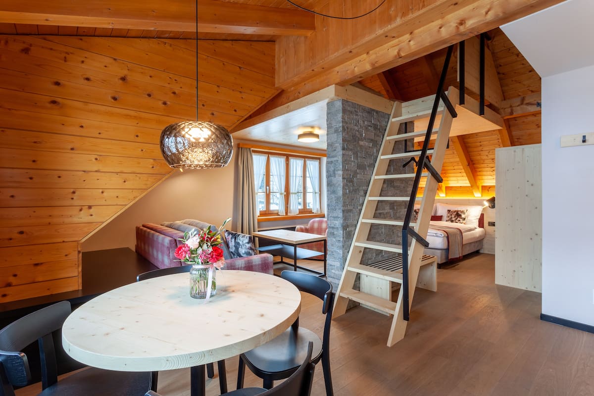 A wooden interior with a dining area, a staircase, and a cozy seating area.