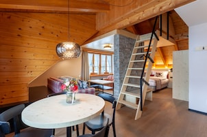 A wooden interior with a dining area, a staircase, and a cozy seating area.