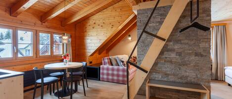 Un interior de madera con una zona de comedor, una pared de piedra y una escalera.