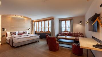 Una habitación de hotel moderna con una cama, un sofá, una mesa de comedor y un televisor.