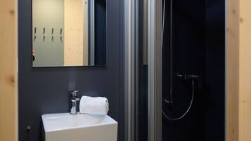 Een badkamer met een wit wastafel, een spiegel en een douche met glazen wanden.