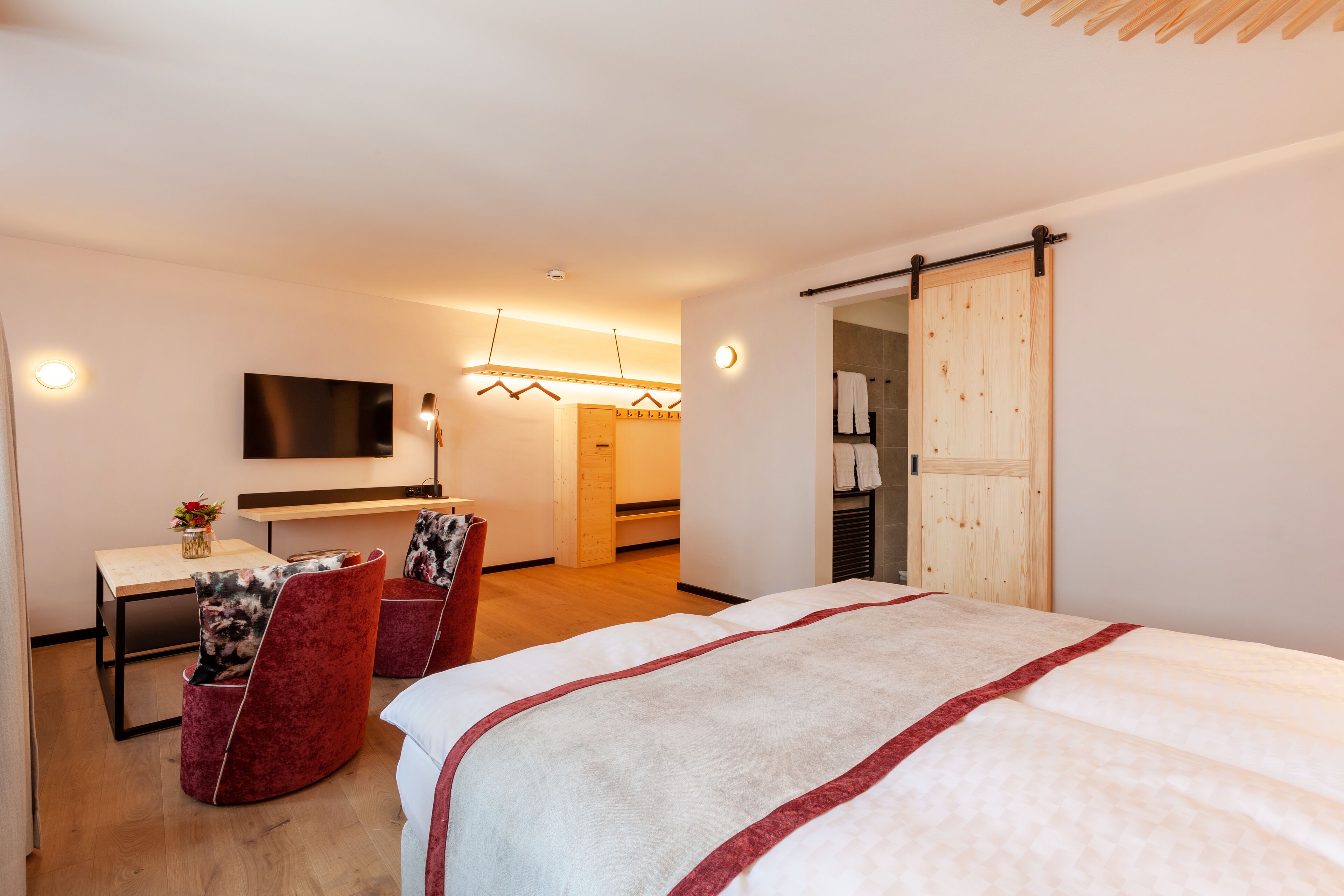 A modern hotel room with a bed, a desk, a TV, and a sliding door.