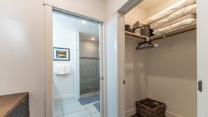 A modern bathroom with a glass shower, a wooden vanity, and a walk-in closet with neatly folded towels. - River West Condos #714 by Summit County Mountain Retreats (Silverthorne)