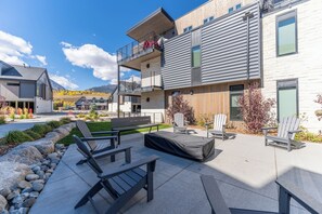 A modern building with a balcony, outdoor seating area, and a view of the mountains.