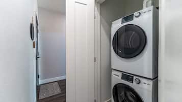 A laundry room with two stacked front-loading washing machines and a dryer.