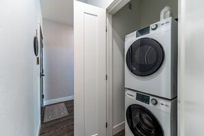 A laundry room with two stacked front-loading washing machines and a dryer.