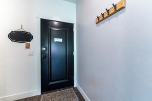 Uma porta preta com uma placa, um porta-roupas de madeira e um tapete estampado.