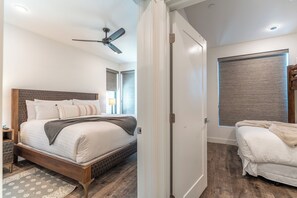 A bedroom with a bed, a nightstand, a ceiling fan, a window with blinds, and a door. - River West Condos #714 by Summit County Mountain Retreats (Silverthorne)