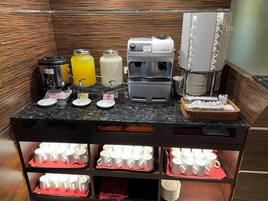 A self-service beverage station with coffee machines, juice dispensers, and a milk station.
