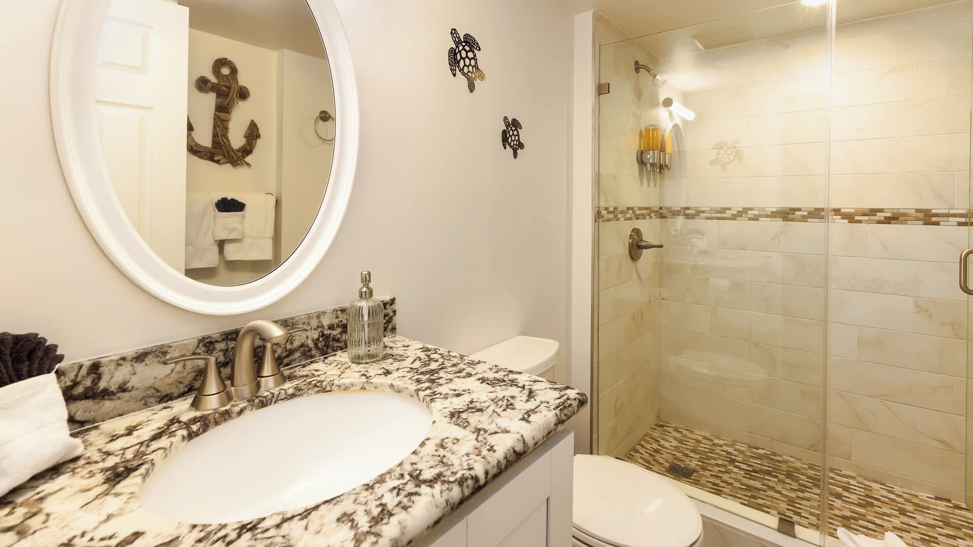 Une salle de bain avec un lavabo en marbre, des toilettes et une douche à parois de verre.