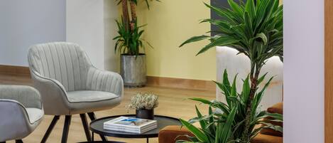A modern lobby with a seating area, two potted plants, and a decorative wall piece.