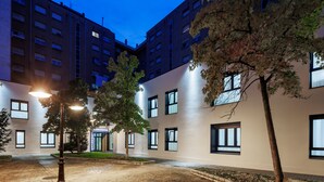 A multi-story building with a courtyard, featuring a tree and a street lamp. - APARTAMENTOS CONGRESO PARKING GRATUITO (Logroño)