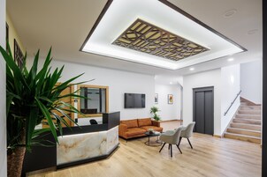 A modern reception area with a marble reception desk, a sofa, and a staircase.