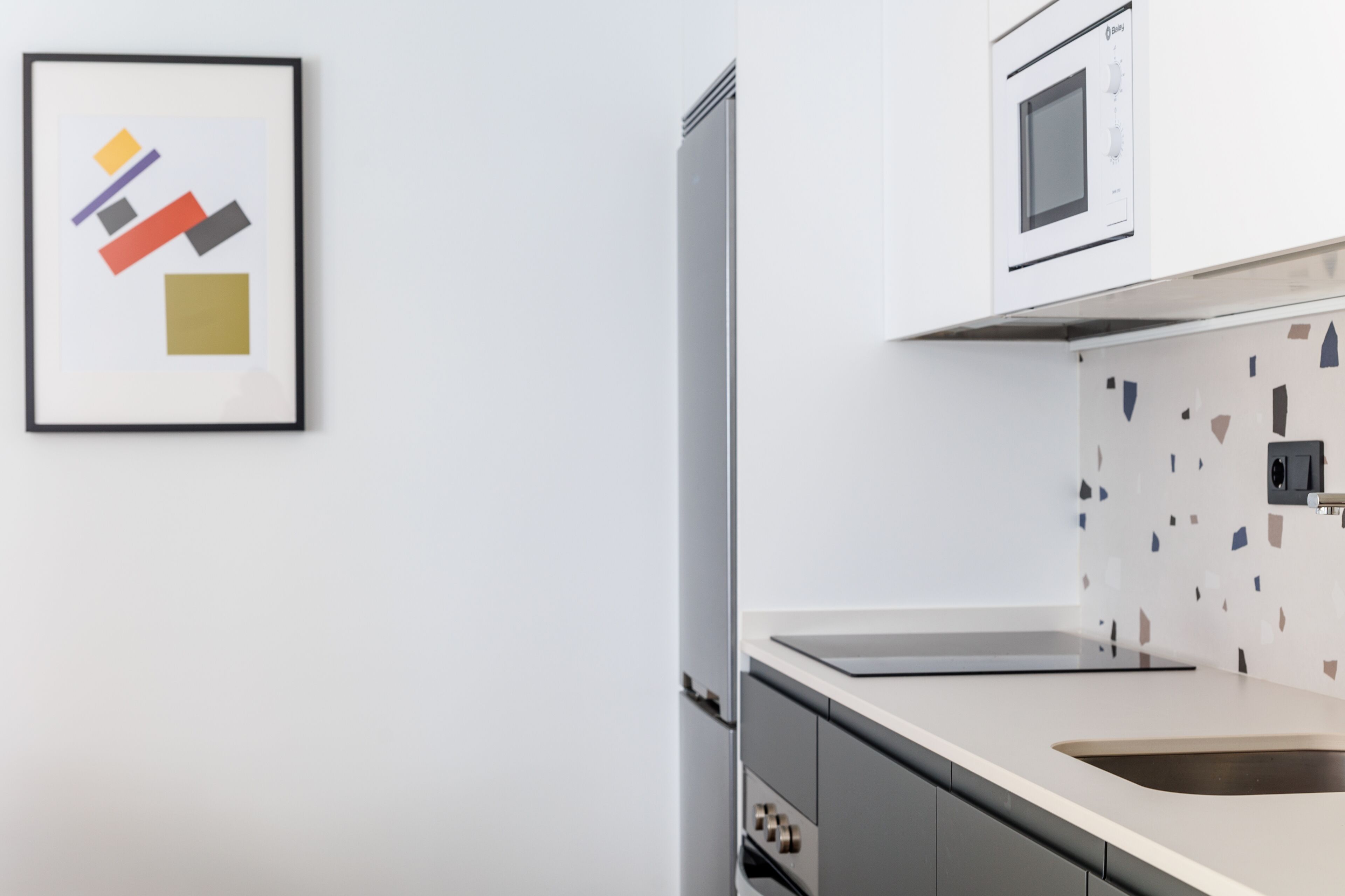 A modern kitchen with a stainless steel refrigerator, a microwave, and a countertop with a sink.