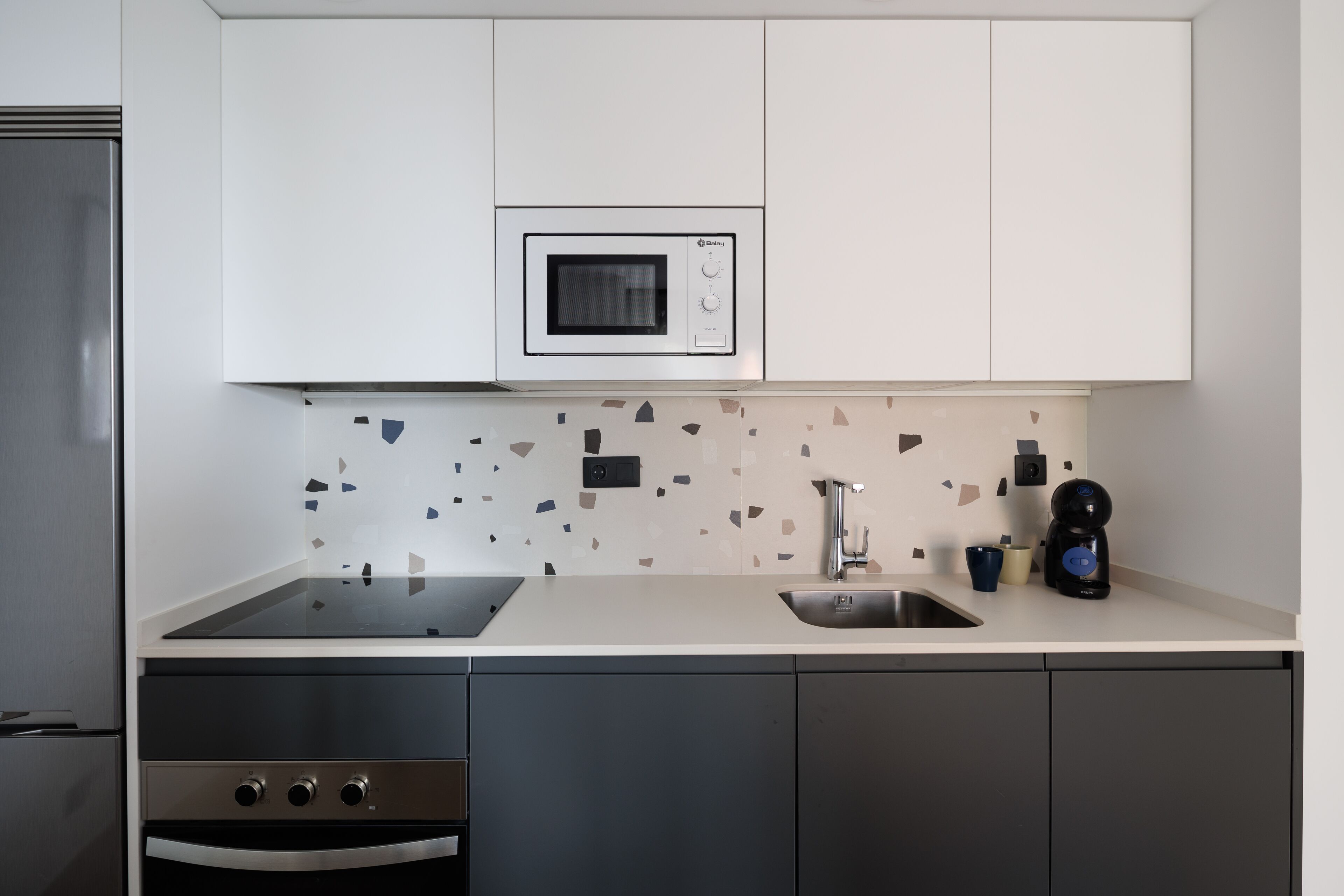 A modern kitchen with a built-in microwave, a sink, and a coffee maker.