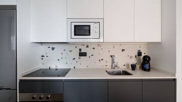A modern kitchen with a built-in microwave, a sink, and a coffee maker.