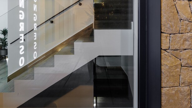 A modern interior with a staircase, a glass wall reflecting the interior, and a stone wall. - APARTAMENTOS CONGRESO PARKING GRATUITO (Logroño)