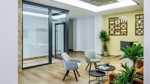 A modern lobby with a wooden floor, two armchairs, a coffee table, and a potted plant. - APARTAMENTOS CONGRESO PARKING GRATUITO (Logroño)