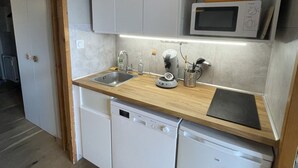 Une cuisine compacte équipée d’un four à micro-ondes, d’une machine à café et d’un lave-vaisselle.
