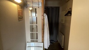 Une petite pièce comprenant un lit, un miroir, un porte-manteau et un panneau indiquant que la bière est offerte.