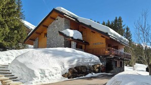 Ein Steinhaus mit Holzfassade und verschneitem Dach.