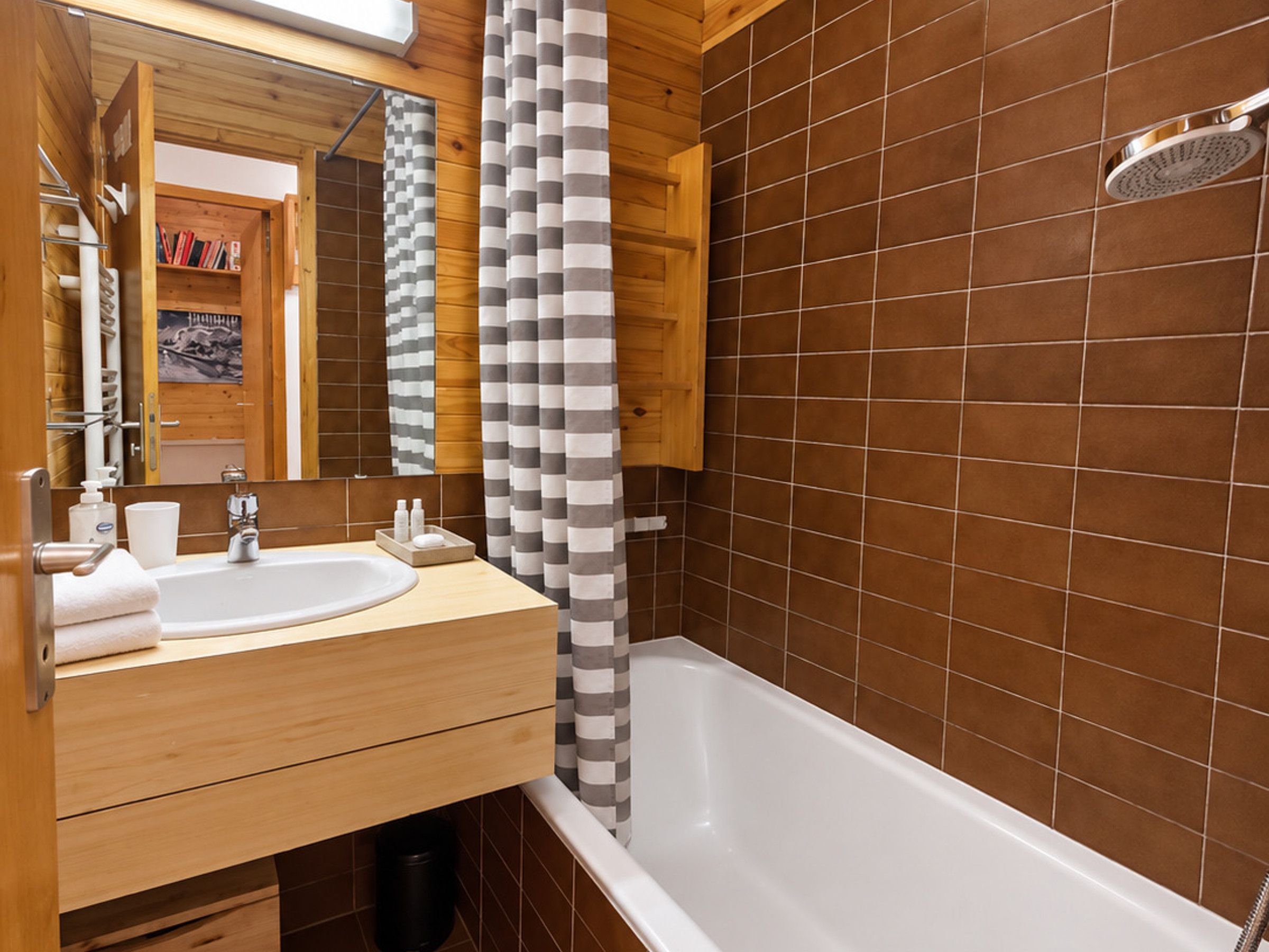 Un baño moderno con tocador de madera, una bañera blanca y un cabezal de ducha.