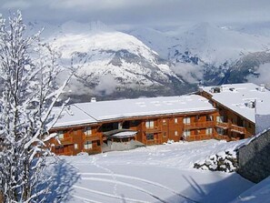 Eine Holzhütte mit schneebedecktem Dach, umgeben von Bergen und Schnee.