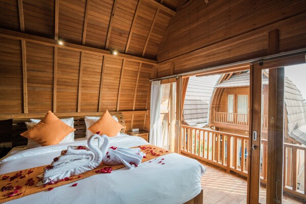 A wooden cabin-style bedroom with a bed, pillows, and a swan-shaped towel.