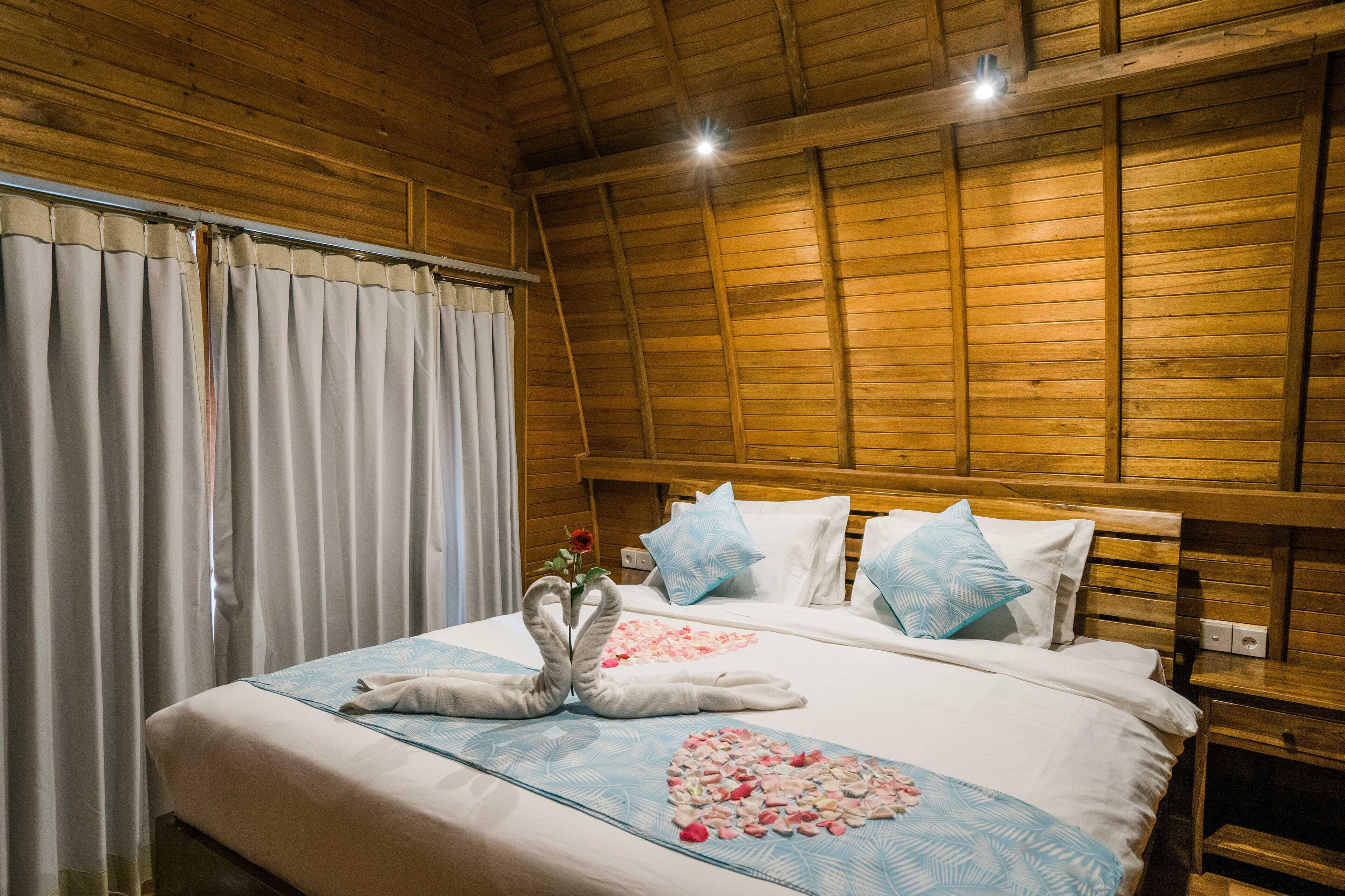 A wooden-paneled room with a bed, curtains, and a ceiling light.