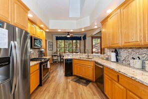 A modern kitchen with wooden cabinets, stainless steel appliances, and a large island.