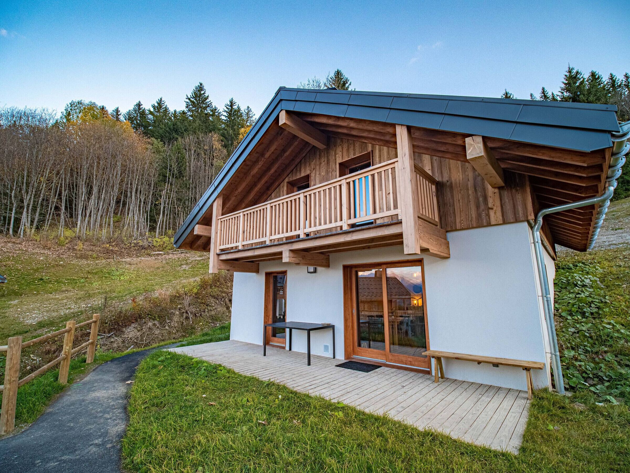 Et moderne træhus med balkon, træterrasse og udsigt over den omkringliggende skov.