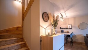 A modern kitchen with a wooden staircase, a dining area with a table and chairs, and a wall-mounted clock. - 3* Chalet Valmorel, ski-in/ski-out, 3 bedrooms, parking, WIFI (Valmorel)