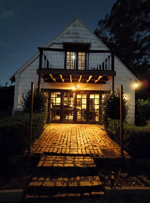 A white house with a covered porch and a brick pathway leading to the entrance. - Firefly Resort: House & Cottage on 10 acres. BBQ deck, pool, tennis court, lawns (Firefly)