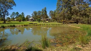 A serene lakeside setting with a house, trees, and a grassy area. - Firefly Resort: House & Cottage on 10 acres. BBQ deck, pool, tennis court, lawns (Firefly)