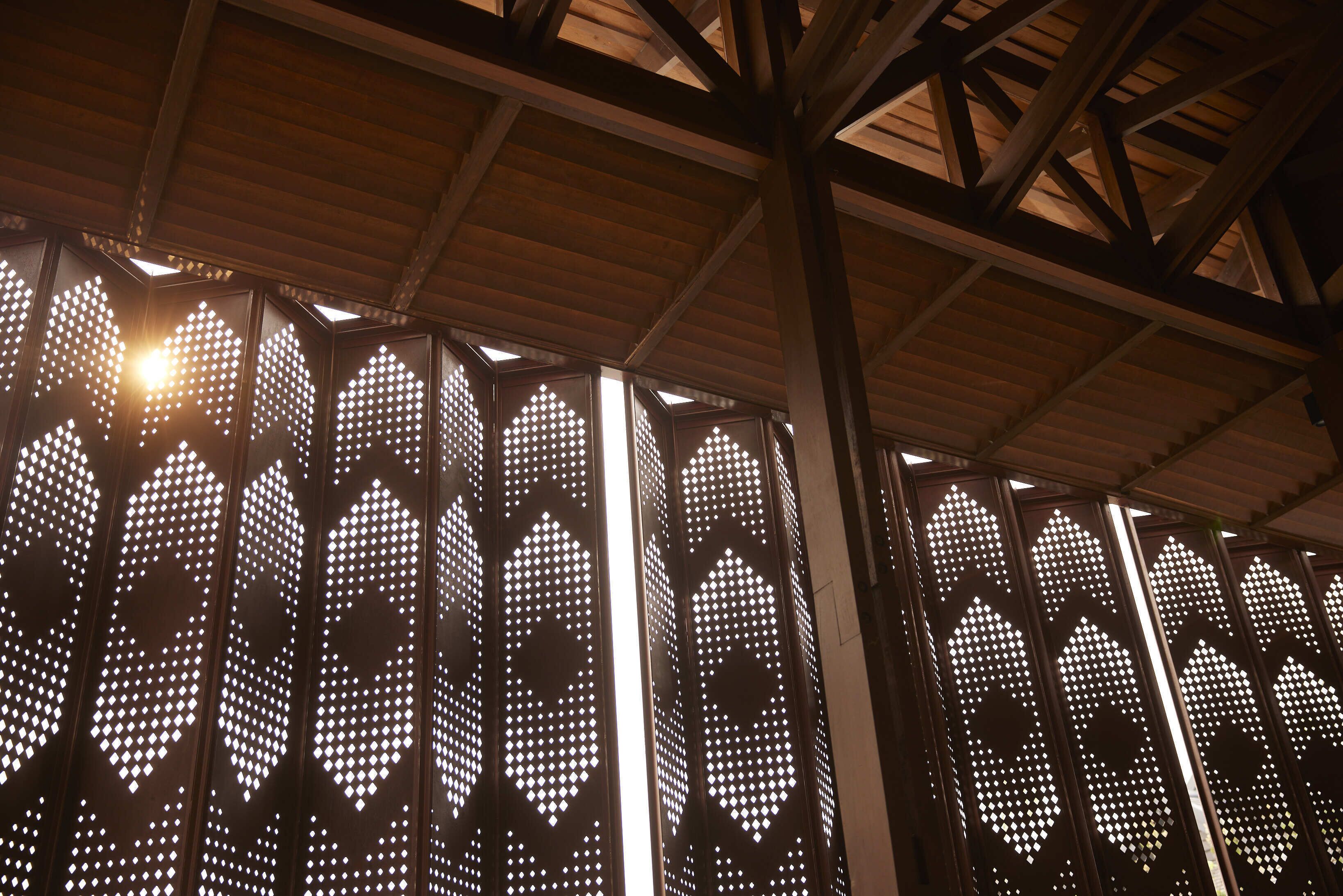 A series of vertical panels with geometric cut-out patterns, likely part of a building's interior design.