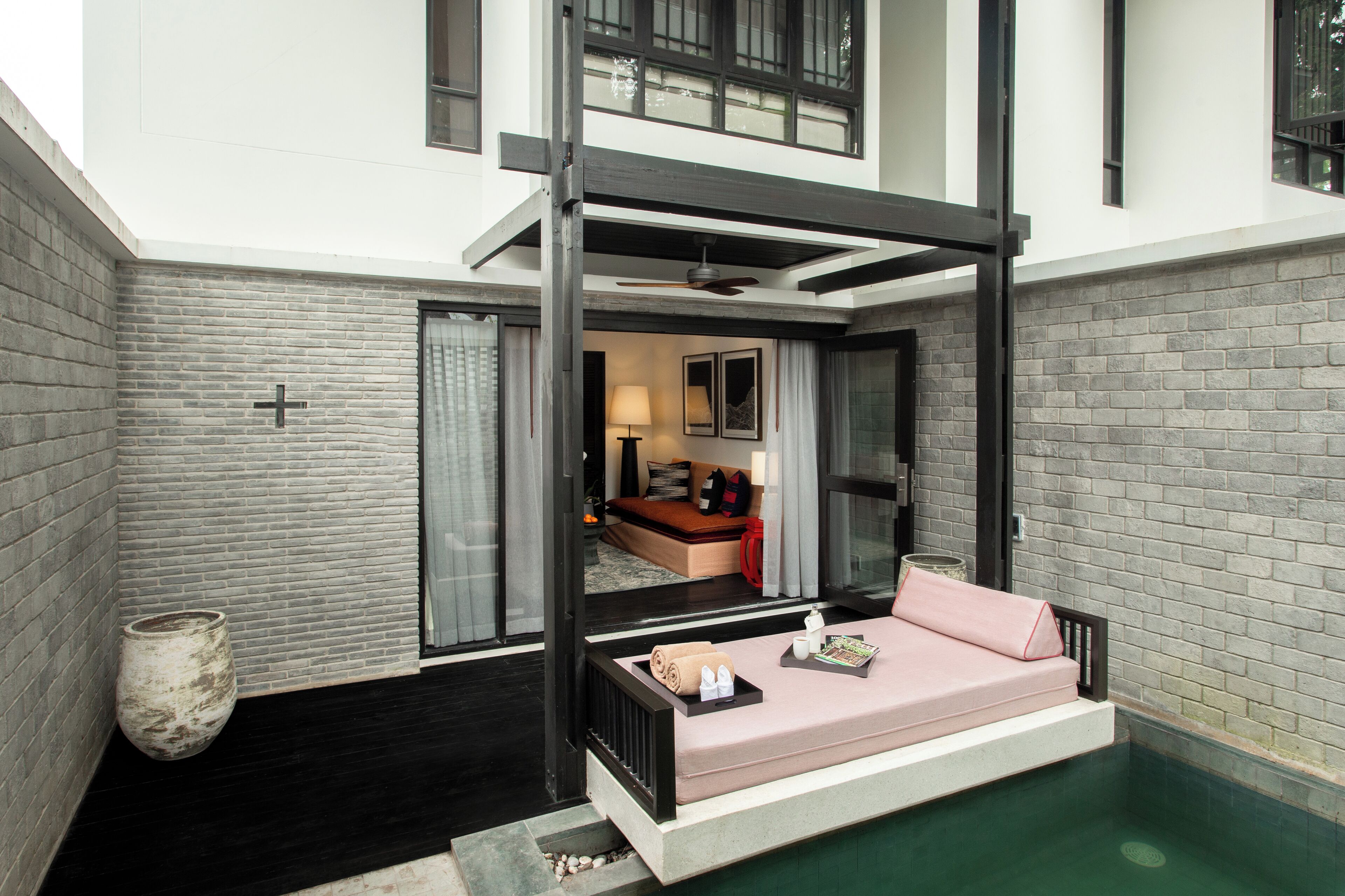Una habitación de hotel moderna con una zona de estar integrada, una piscina pequeña y una sala de estar separada con sofá y mesa de comedor.