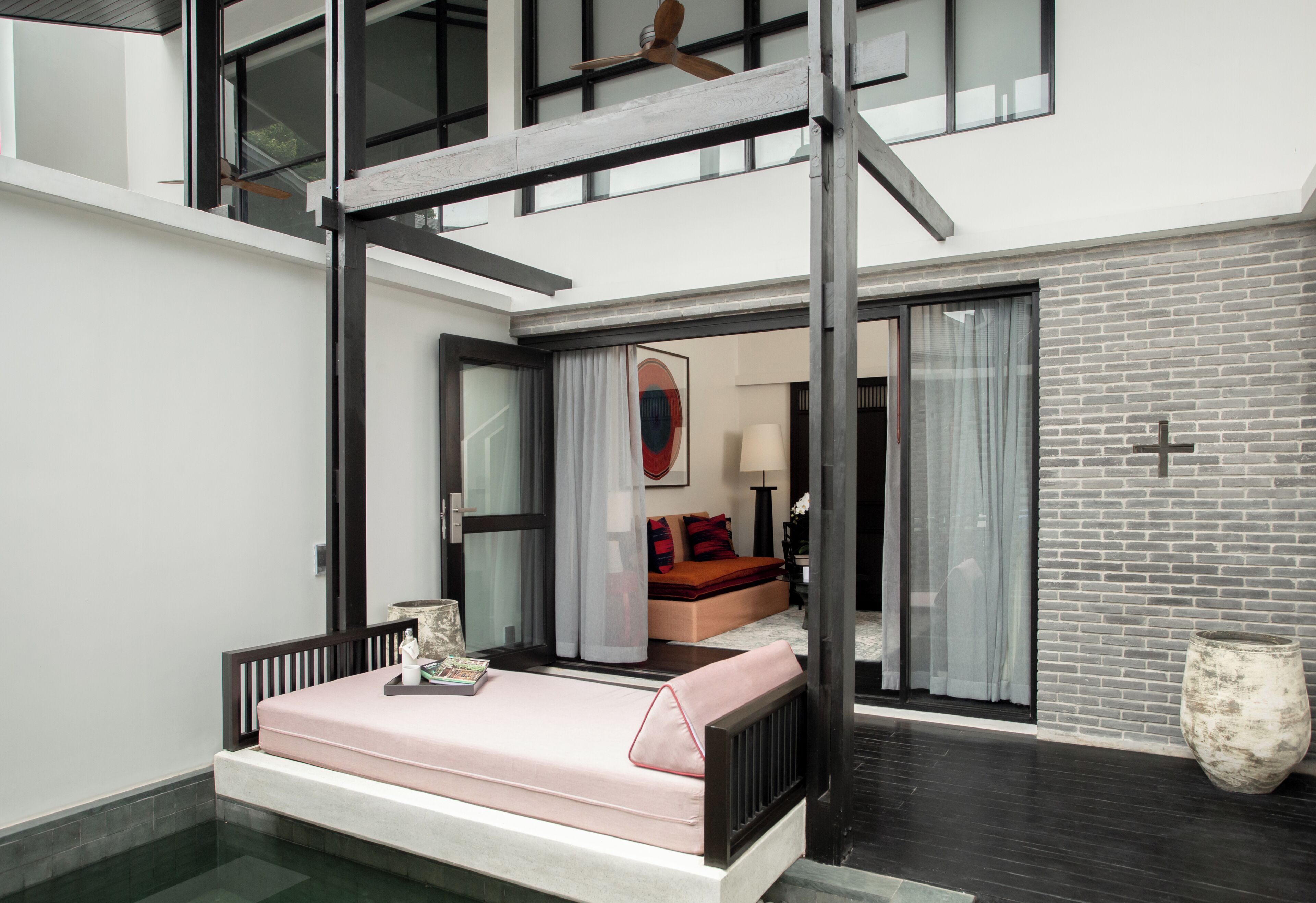 A modern bedroom with a bed, a ceiling fan, and a view into an adjacent room.