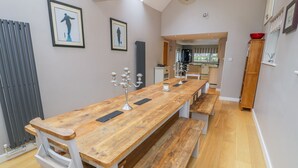 Un'ampia sala da pranzo con un lungo tavolo in legno, panche e un candelabro.