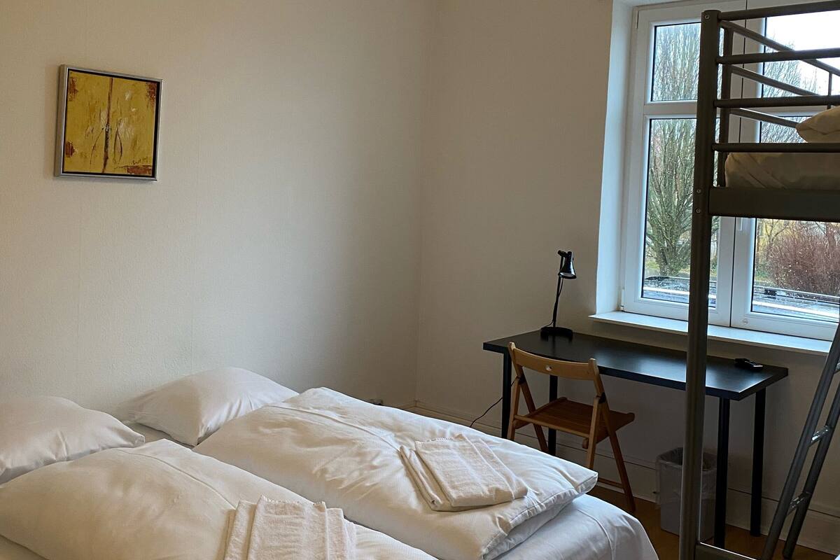 Une chambre avec un lit superposé, un bureau et une fenêtre.