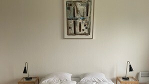 A double bed with white linens and two bedside tables with lamps. - Only Sleep Femern (Holeby)