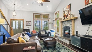 A living room with a fireplace, a television, and a sofa. - Silver Linings - Hot Tub, Mountain Views, Close to Town, Pet Friendly (Waynesville)